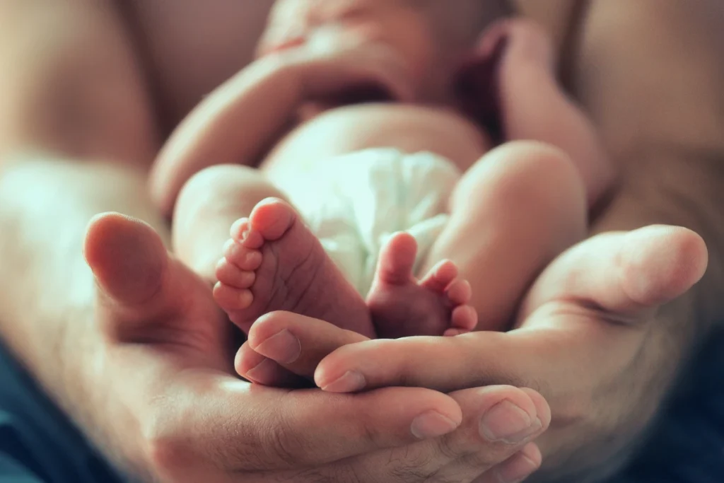 New born baby resting while a parent gently holds their hand